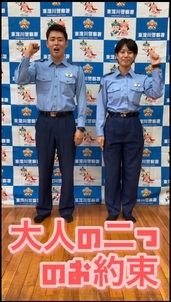 大人の二つのお約束の文字と男女の警察官が並んで腕を上げている写真