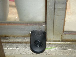 窓の下のレーン部分に取り付けられている黒色で丸いつまみ部分がある補助錠の写真
