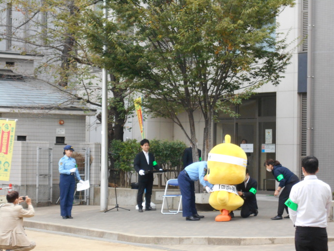 制服を着た警察官の方から一日署長のタスキをかけられているひよこちゃんの写真