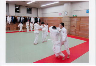道場で子どものたちが2人1組になって互いの柔道着の襟元を掴み、稽古をしている様子の写真