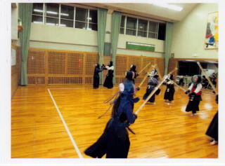 体育館内で2人1組になり、立ち合い稽古をしているこどもたちの写真