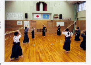 体育館内で面だけ外した子どもたちが竹刀を持ち素振り稽古をしている写真