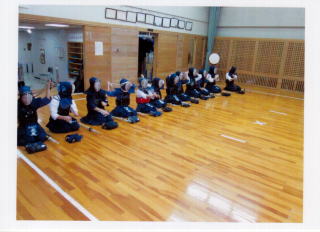 体育館で子どもたちが正座をし、それぞれ竹刀や小手を足元に置き横一列に並んでいる写真