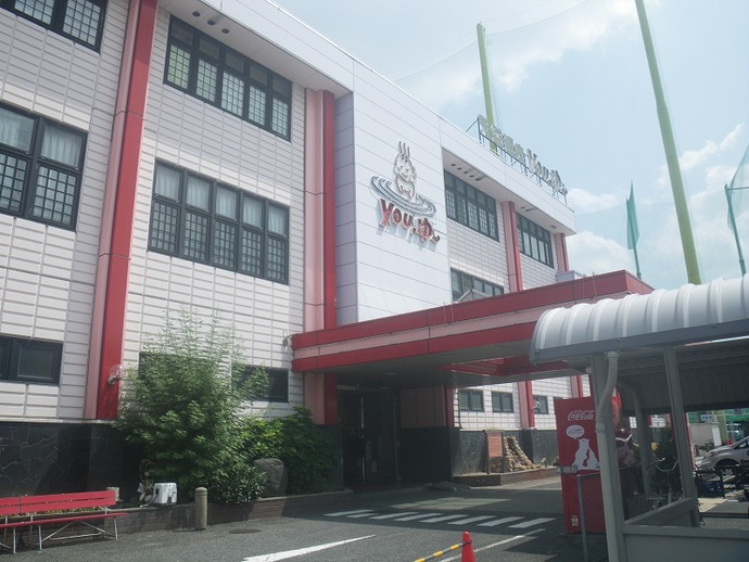 全体的に白の建物で、赤の柱が4本、入口側の屋根が赤い松原天然温泉you、ゆ～の建物の外観の写真